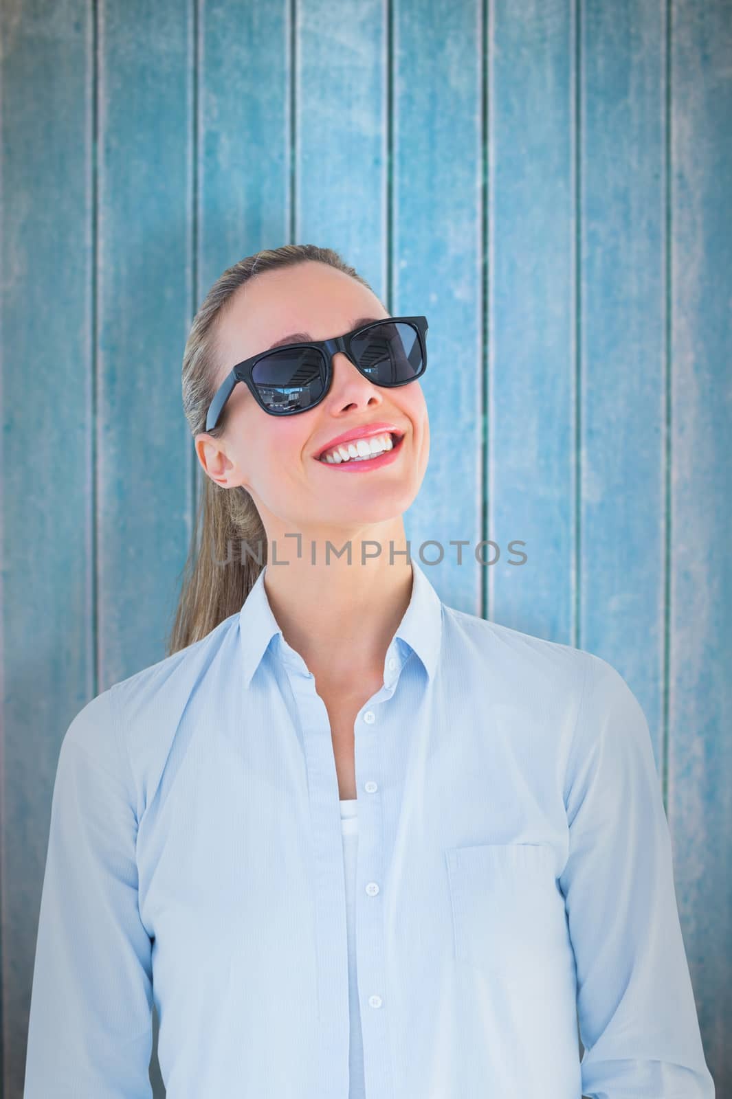 Portrait of smiling blonde wearing sunglasses against wooden planks