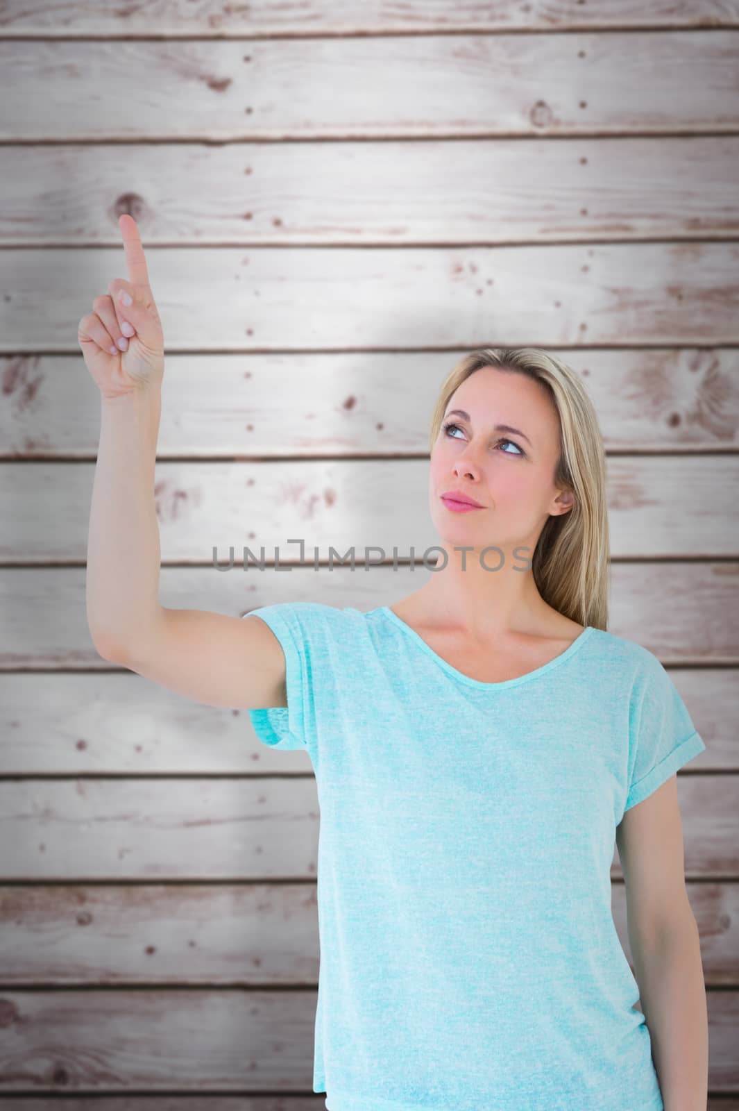 Pretty blonde thinking and pointing up against wooden planks