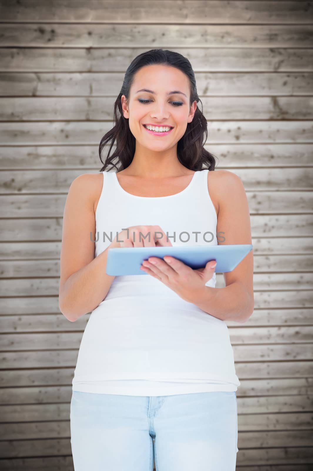 Composite image of pretty brunette using tablet pc by Wavebreakmedia