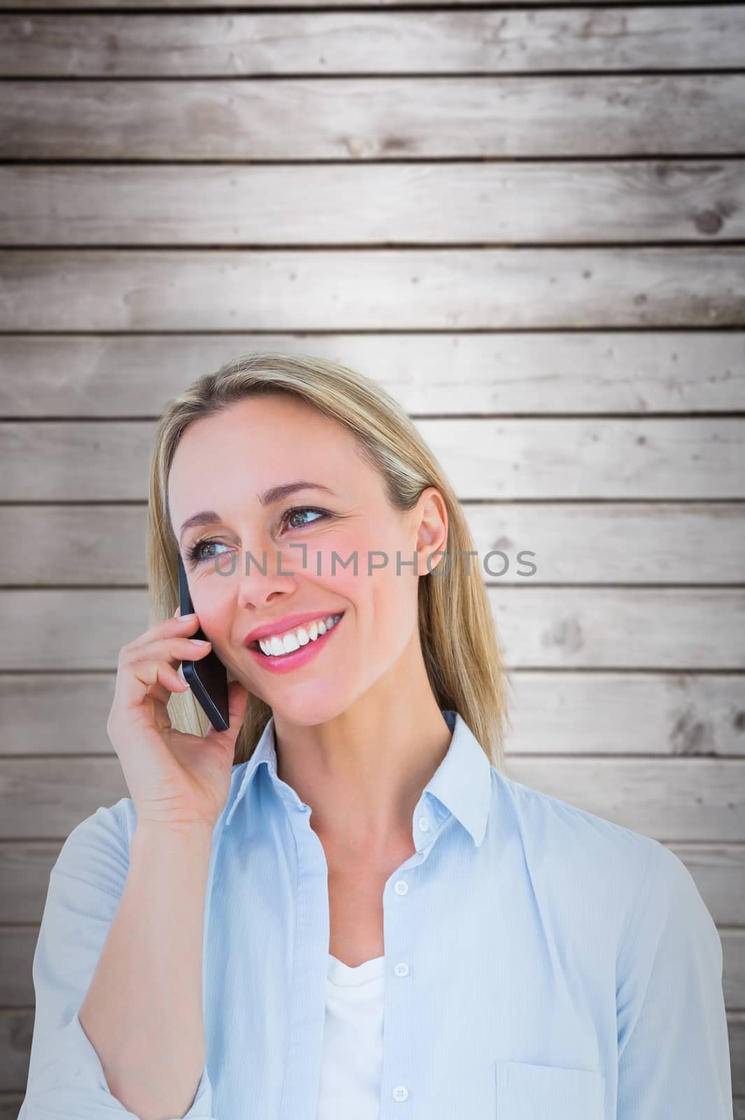 Smiling blonde on the phone standing against wooden planks