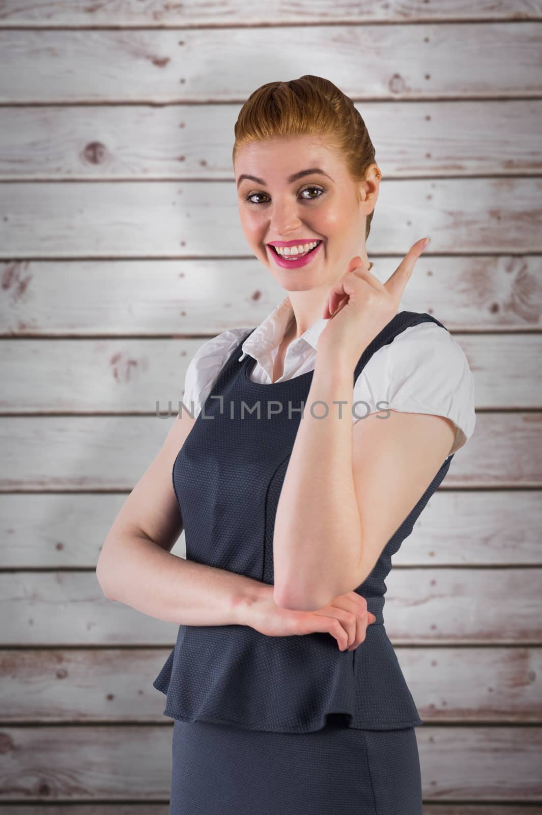 Redhead businesswoman pointing and smiling against wooden planks