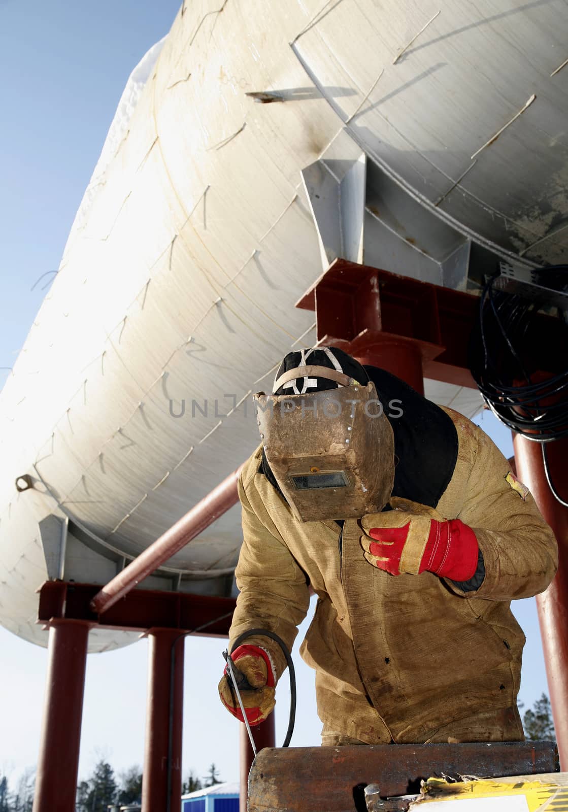 welder working with electrode at arc werding in oil industry winter outdoors