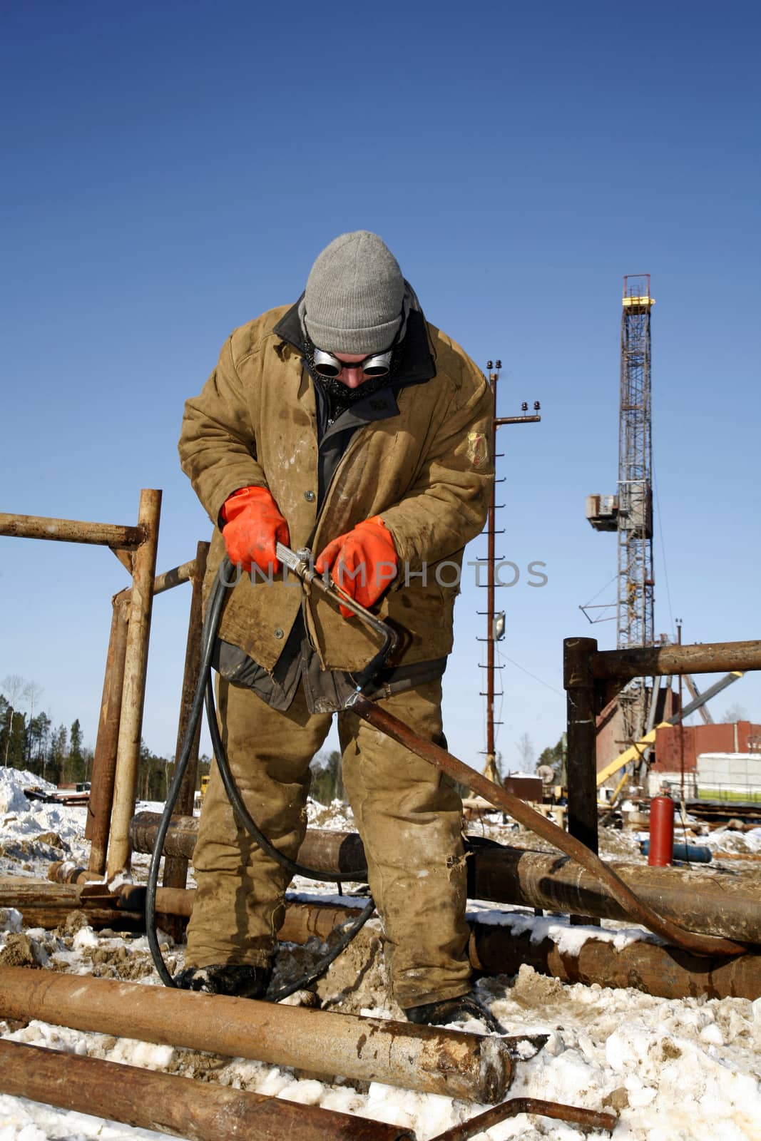 welder working with electrode at arc werding in oil industry winter outdoors