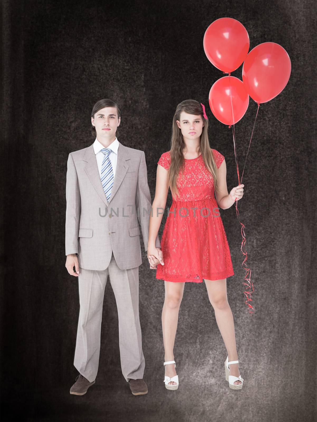 Unsmiling geeky couple standing hand in hand against black background