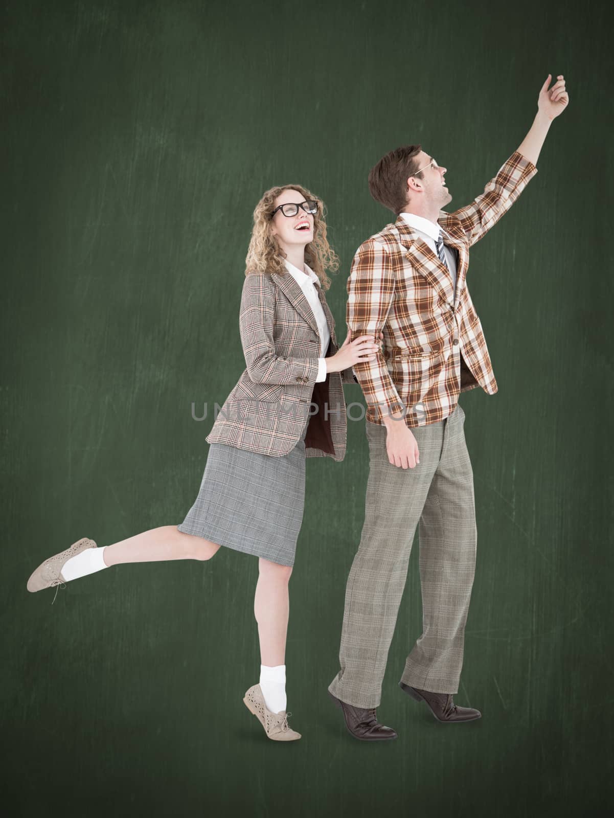 Happy geeky hipster couple holding their hands  against green chalkboard