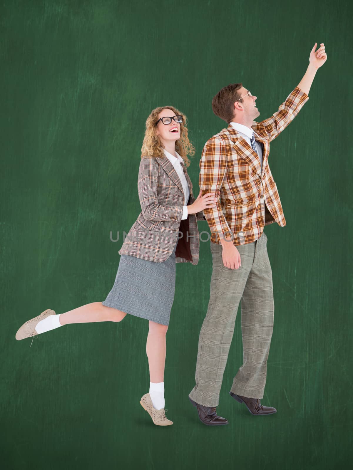 Happy geeky hipster couple holding their hands  against green chalkboard