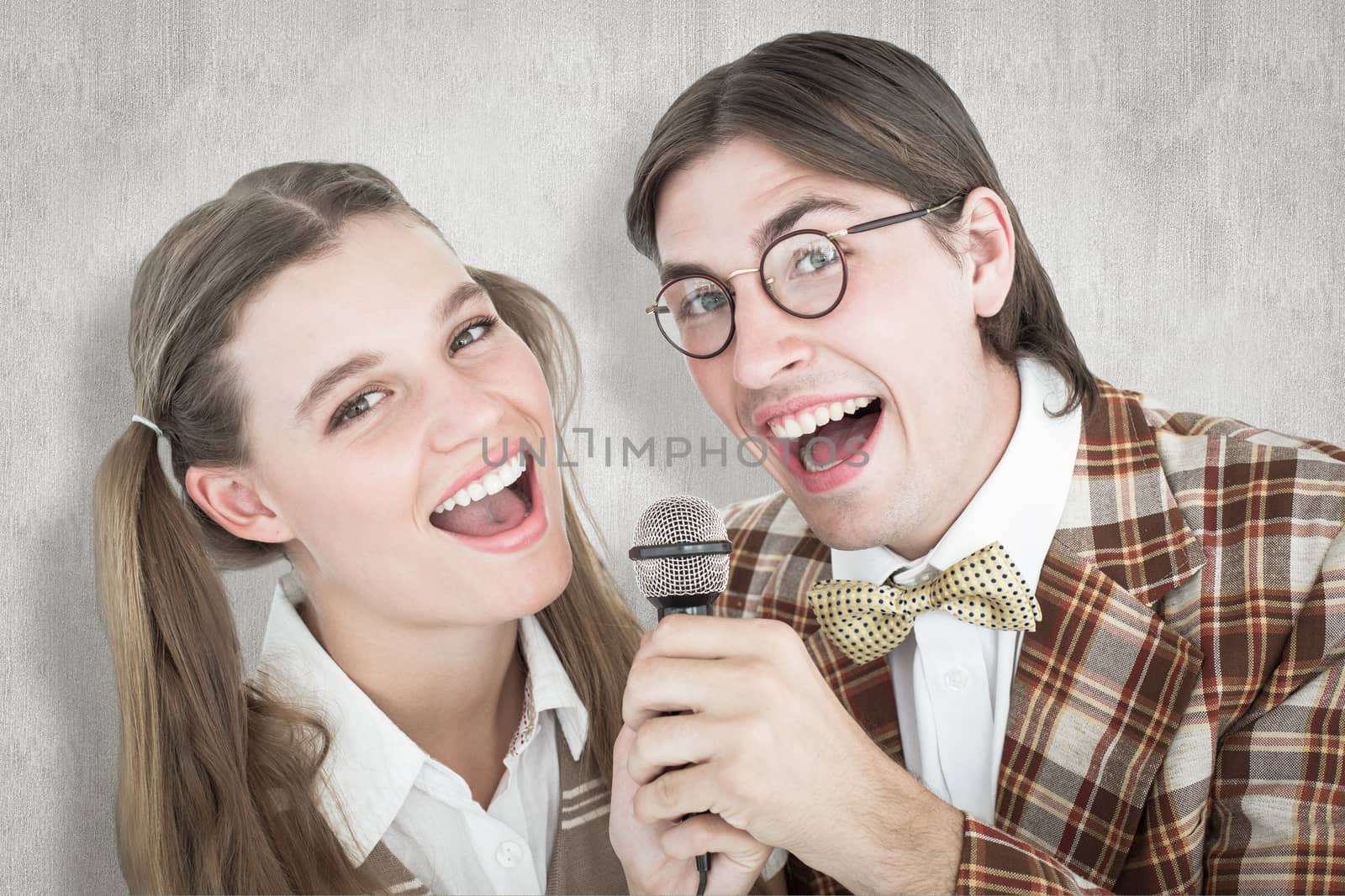 Happy geeky hipsters singing with microphone against white background