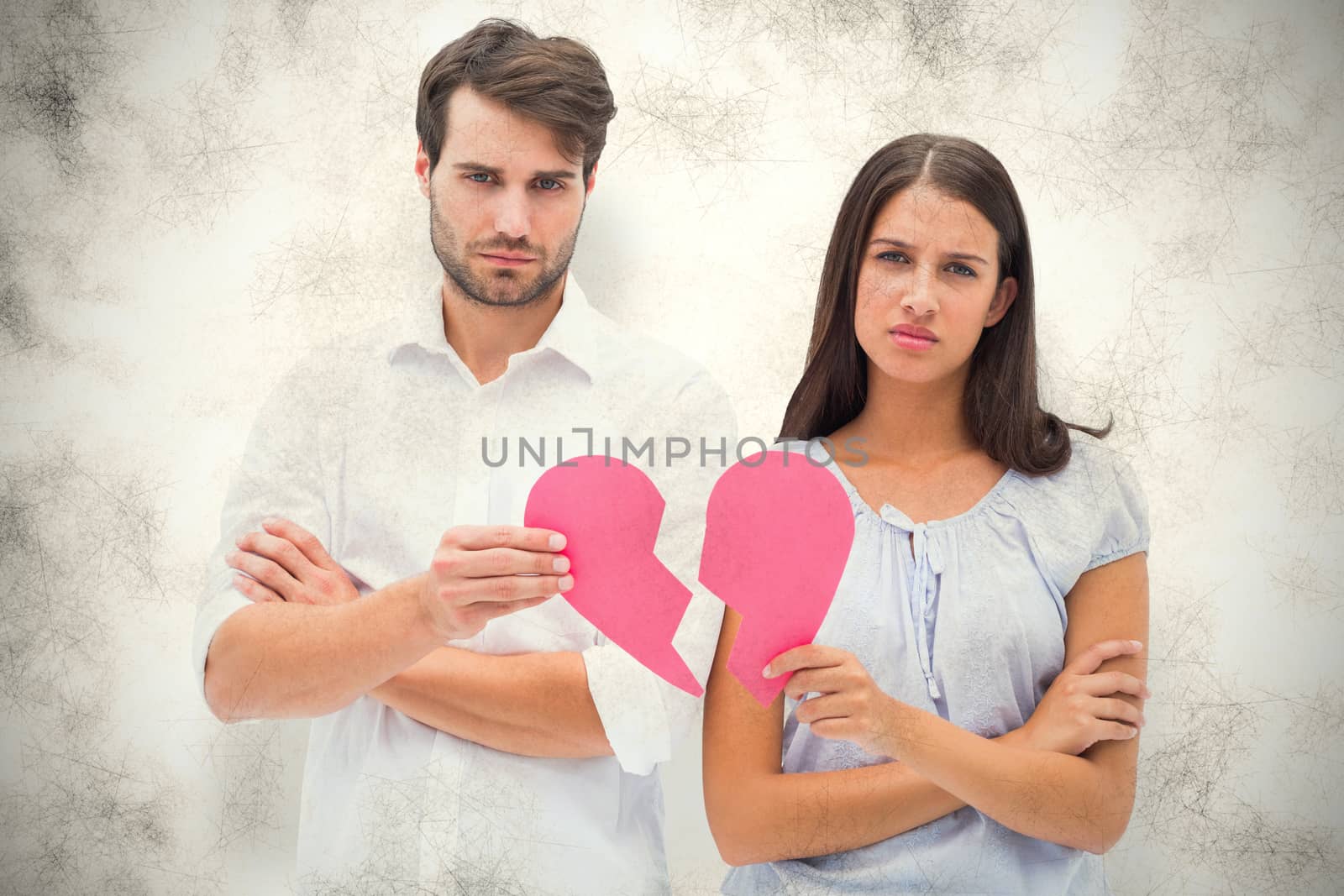 Upset couple holding two halves of broken heart against grey background