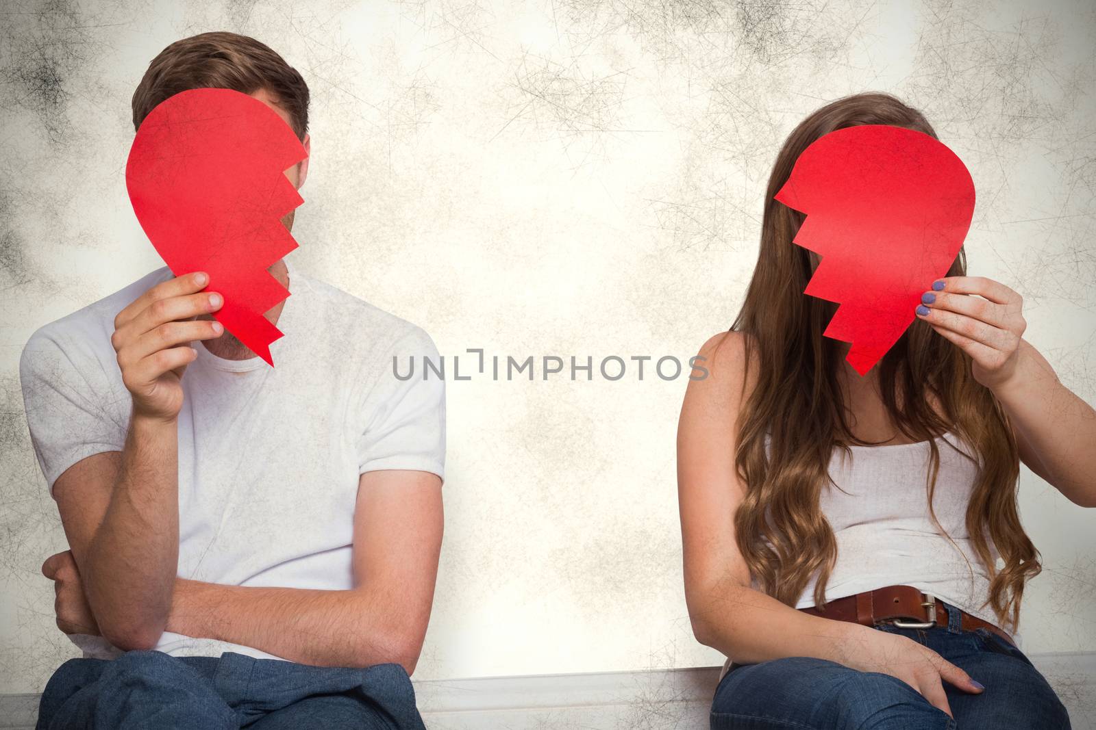 Couple holding broken heart against grey background