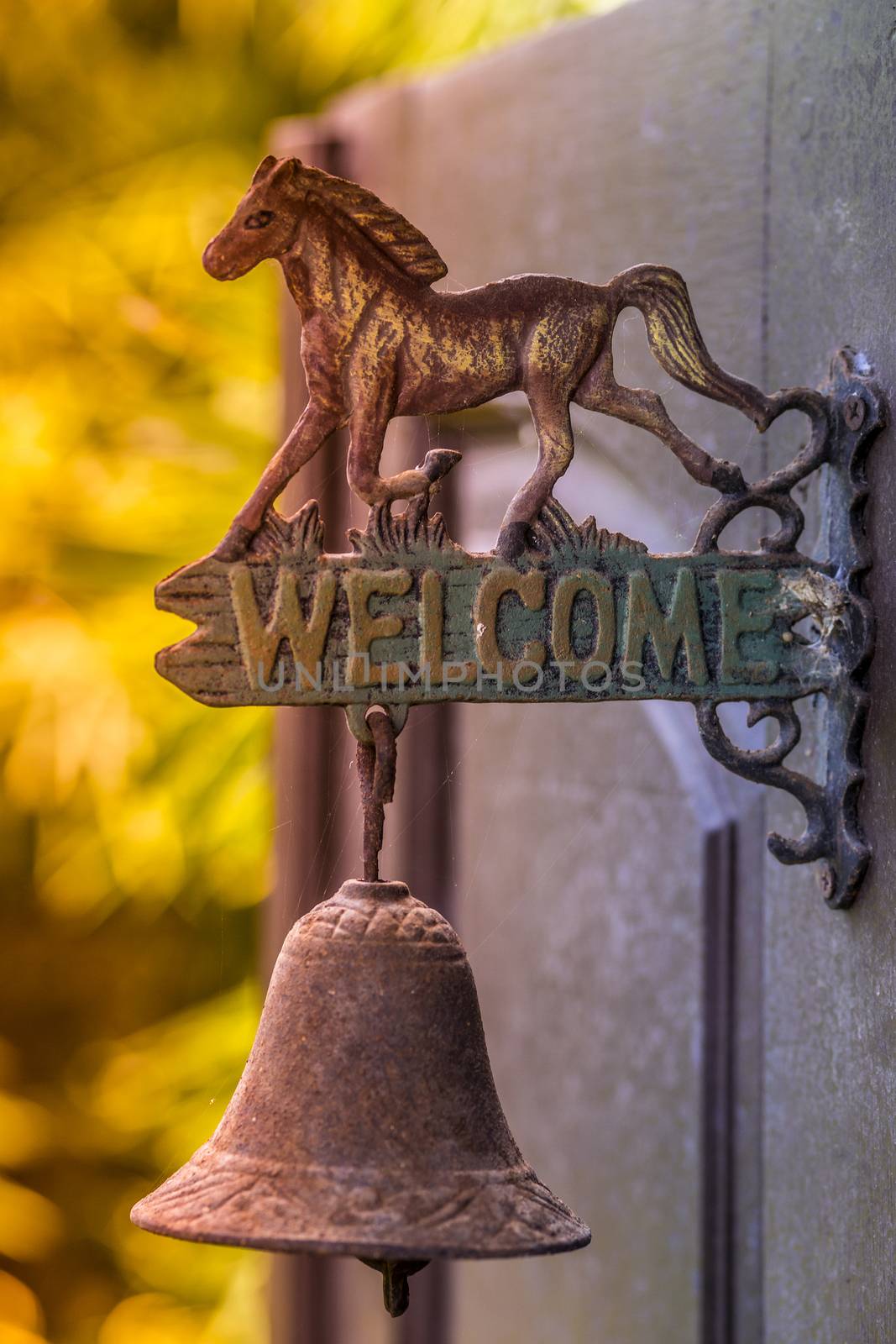 Metal sign welcome on the door with horse sculpture.