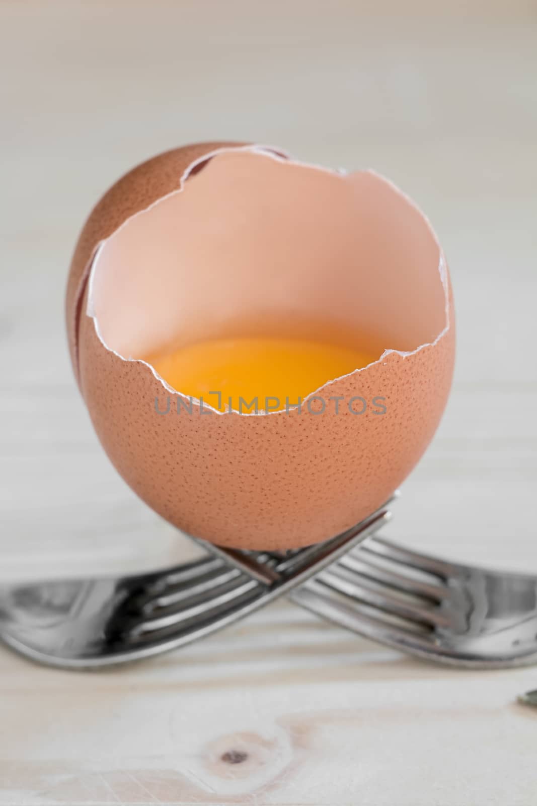 open egg resting on two steel forks