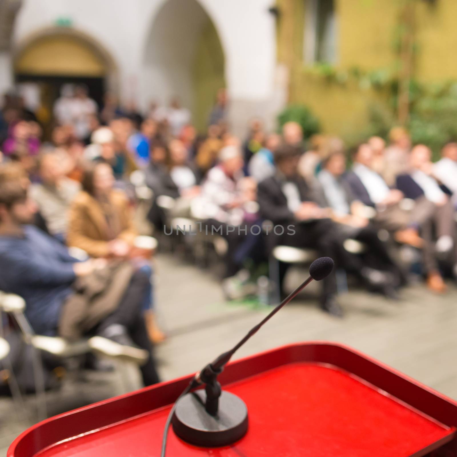 Microphone on a Podium Desk at Business Event. Audience at the conference hall. Business and Entrepreneurship. Business woman. Focus on microphone.