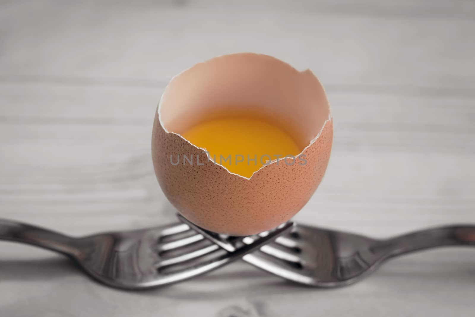 open egg resting on two steel forks