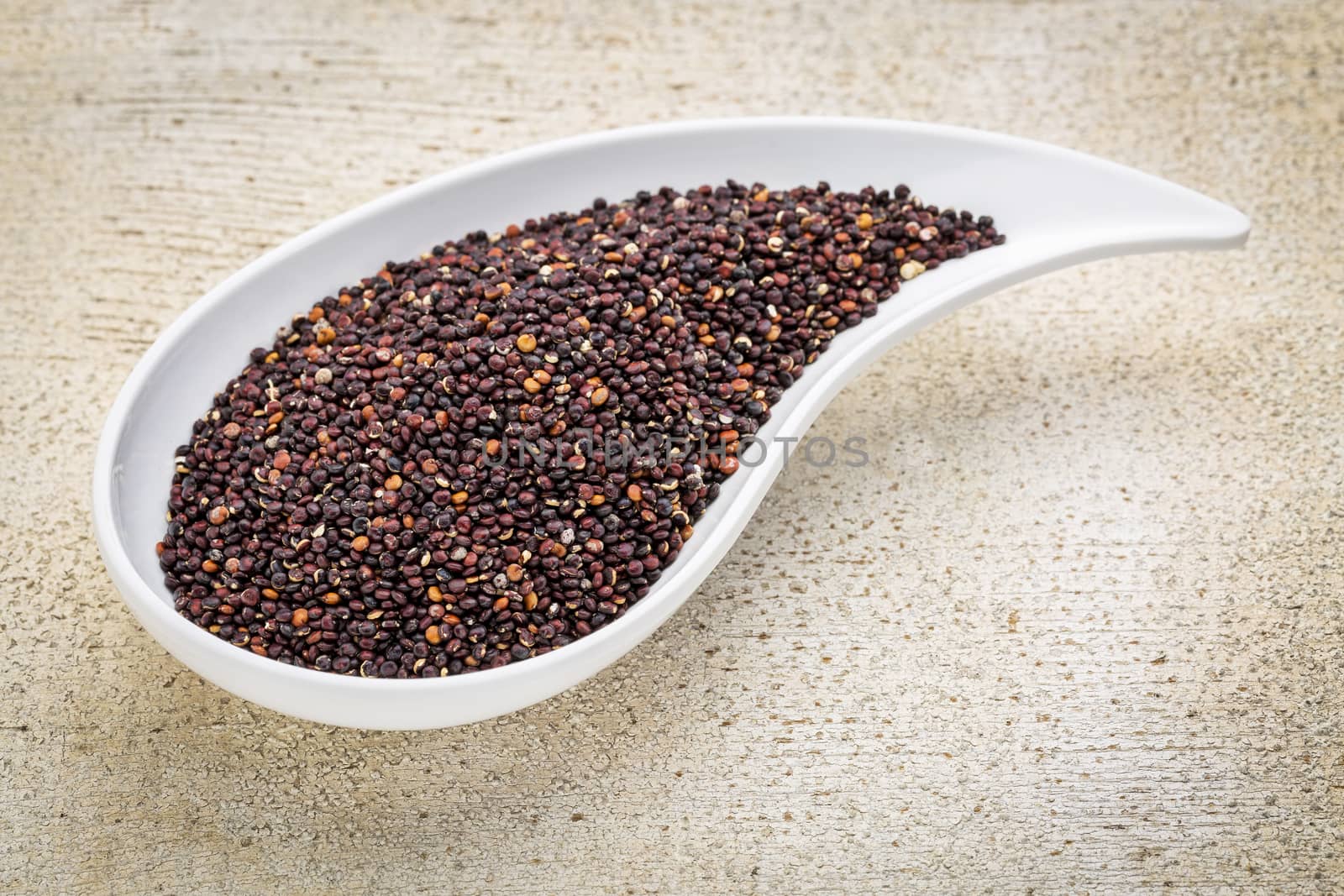 gluten free black quinoa grain grown in Bolivia ,  a teardrop shaped bowl against white painted grunge wood