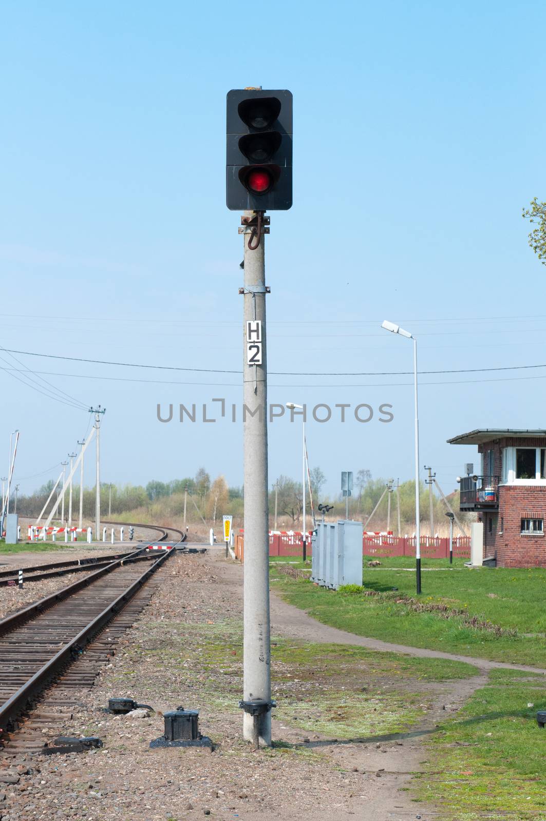 Railroad track and stop light. Traffic light shows red signal on railway.