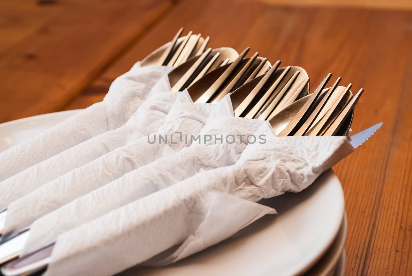 Spoons Forks and Knifes in Napkin Papers on Dishes.