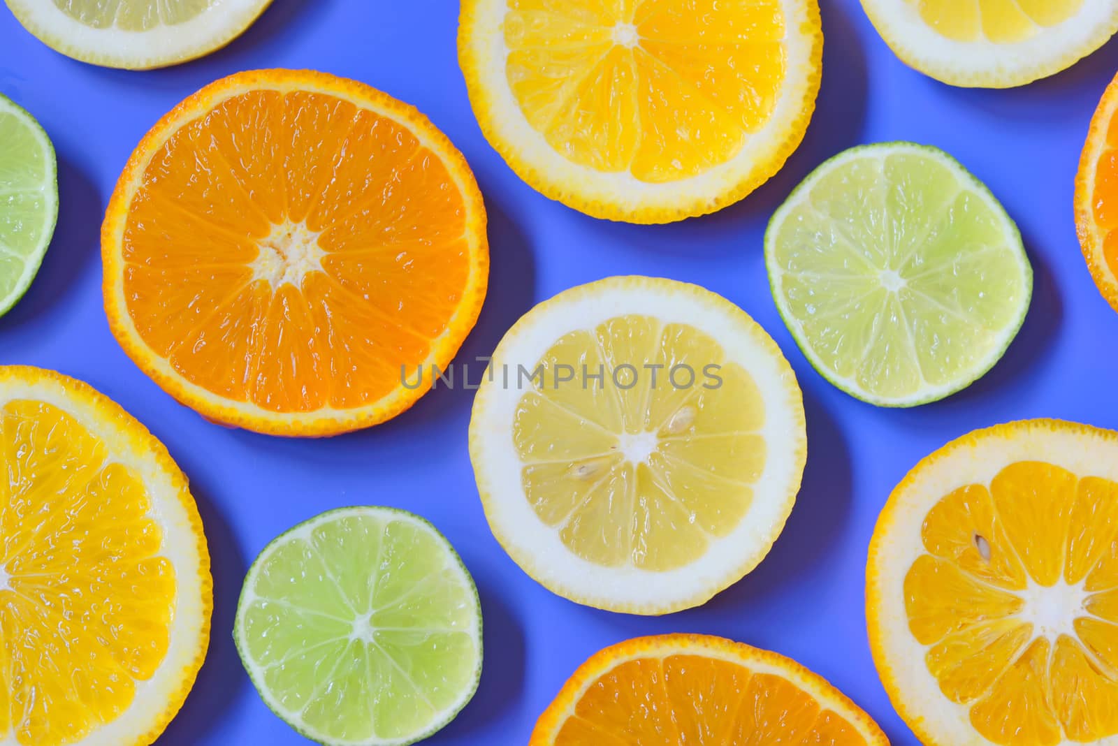 Slices of various citrus fruits on blue background