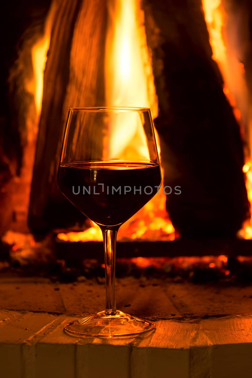 Glass of red vine near fireplace by Nanisimova