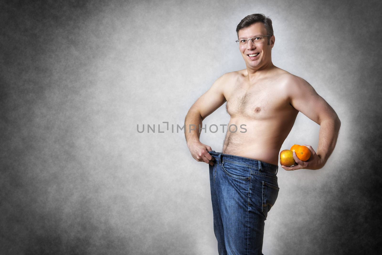 Image of a man in blue jeans with fruits who has lost body weight