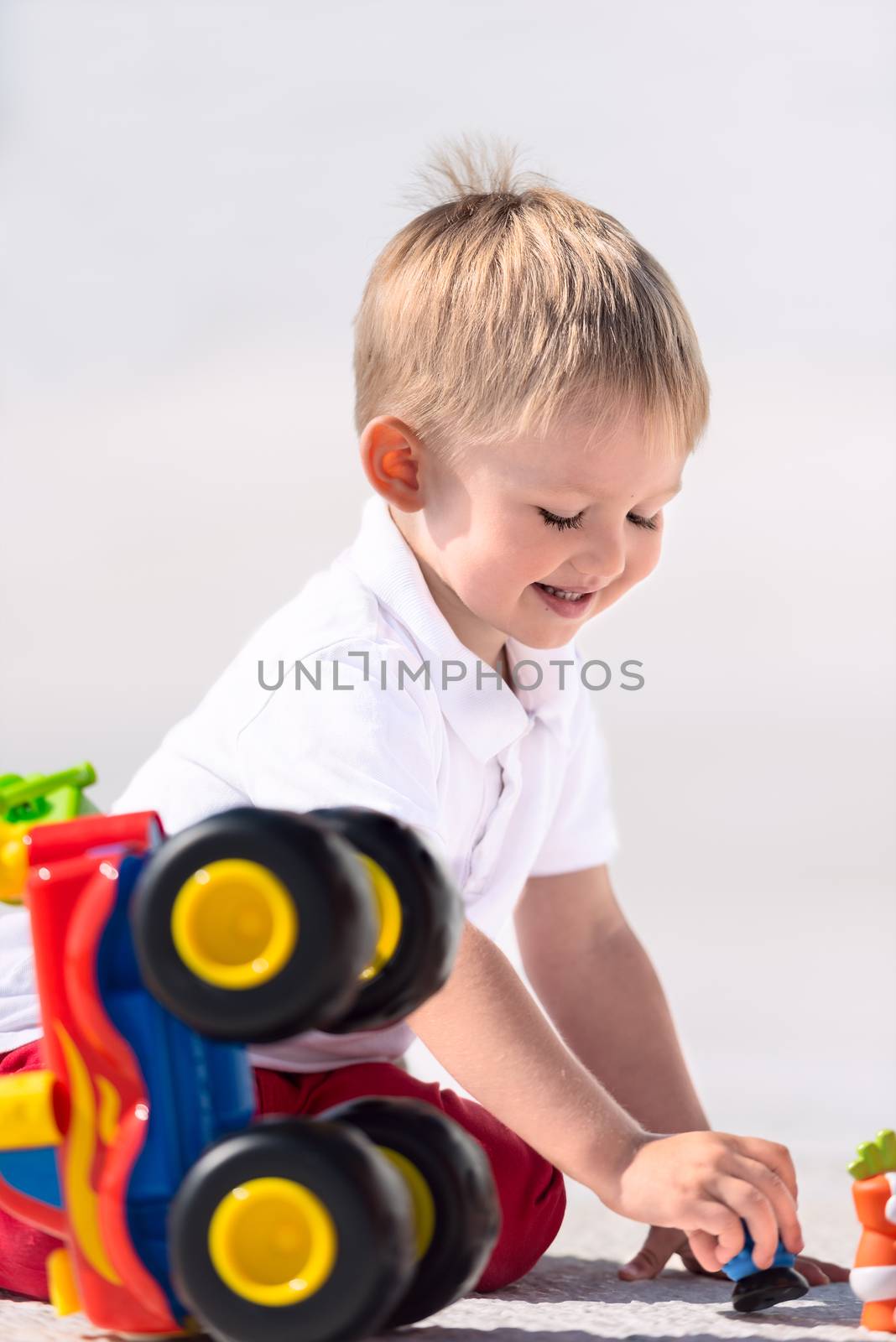 Little boy playing with toy car vertical by Nanisimova