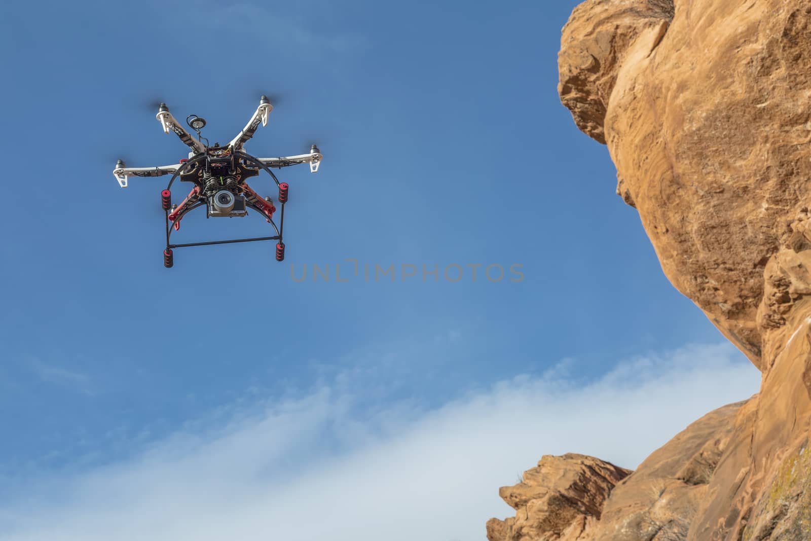 drone flying along sandstone cliff by PixelsAway