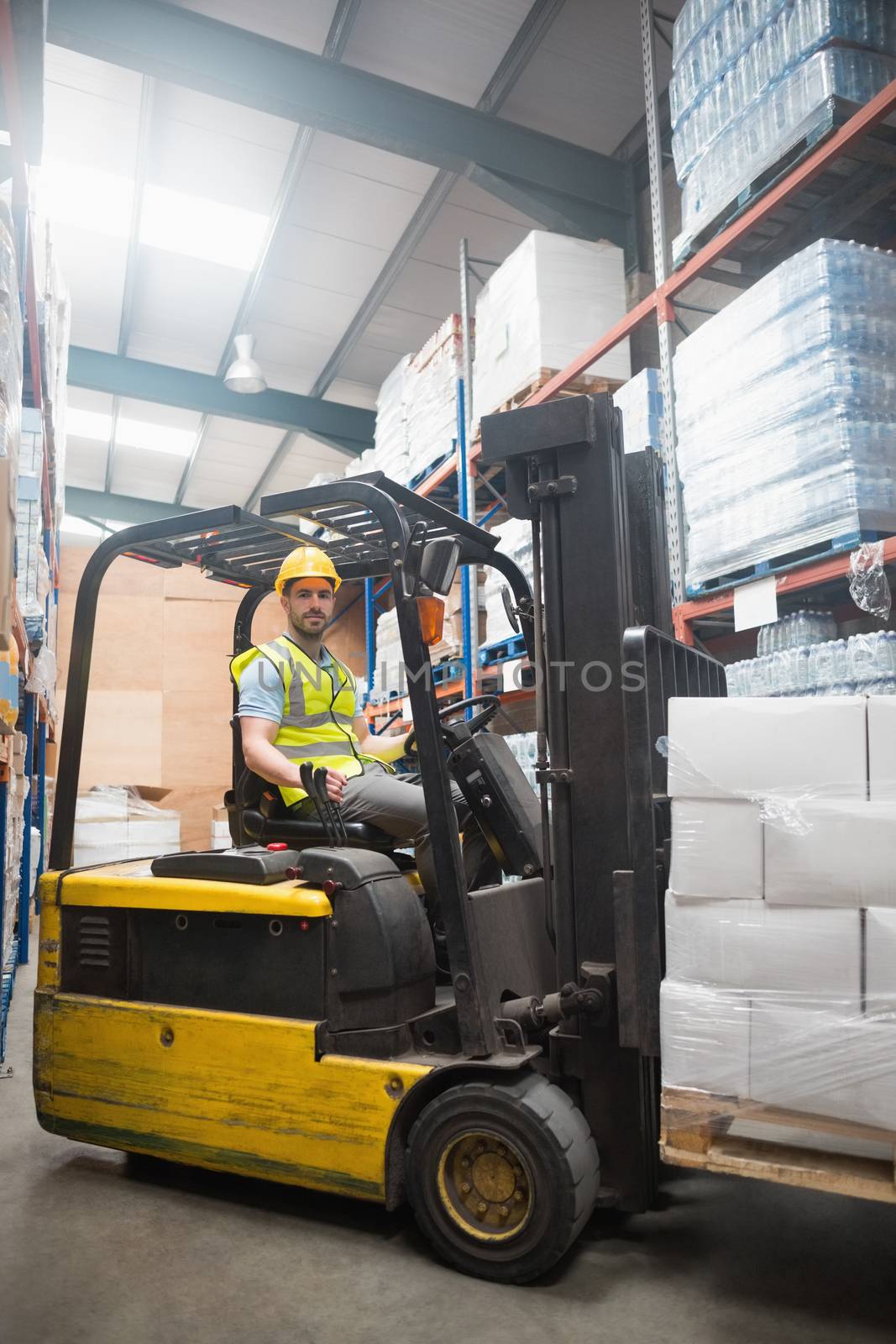 Smiling driver operating forklift machine in warehouse
