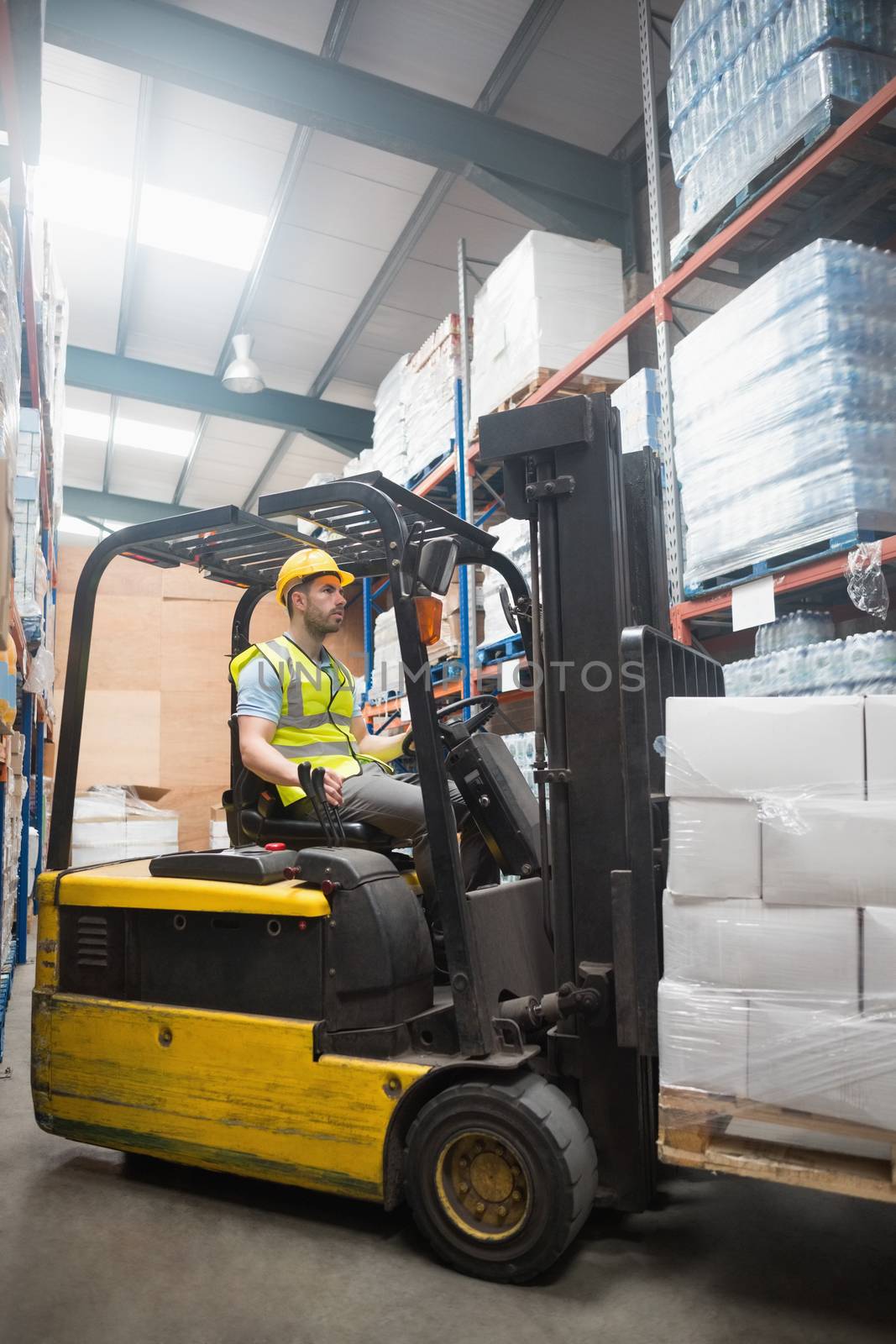 Focused driver operating forklift machine in warehouse