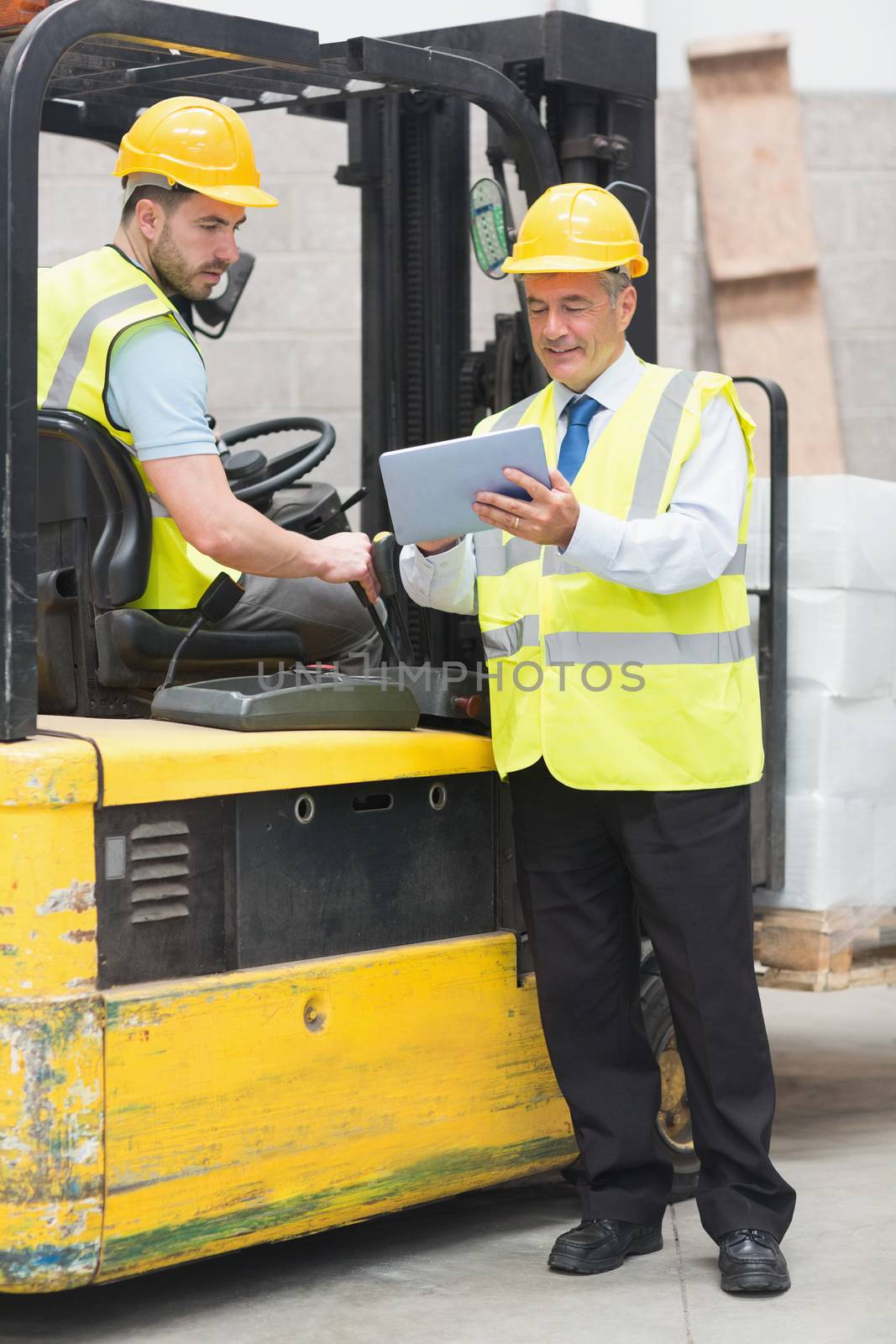 Forklift driver talking with his manager in a large warehouse