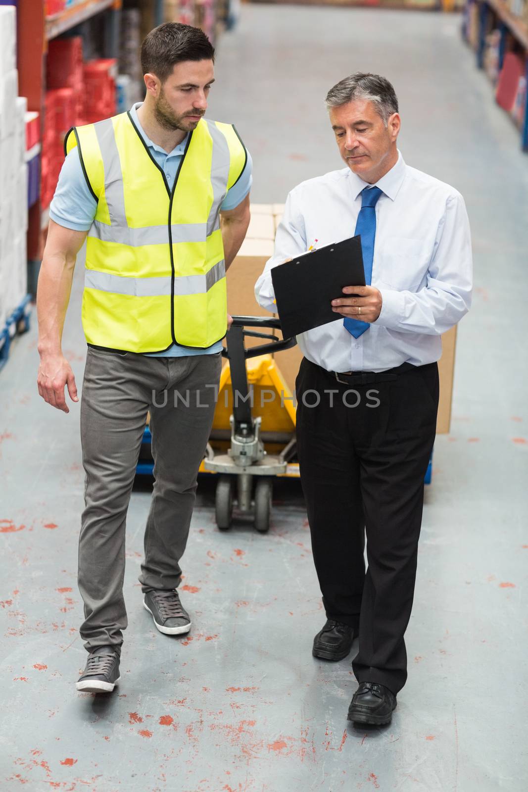 Warehouse worker talking with his manager in a large warehouse