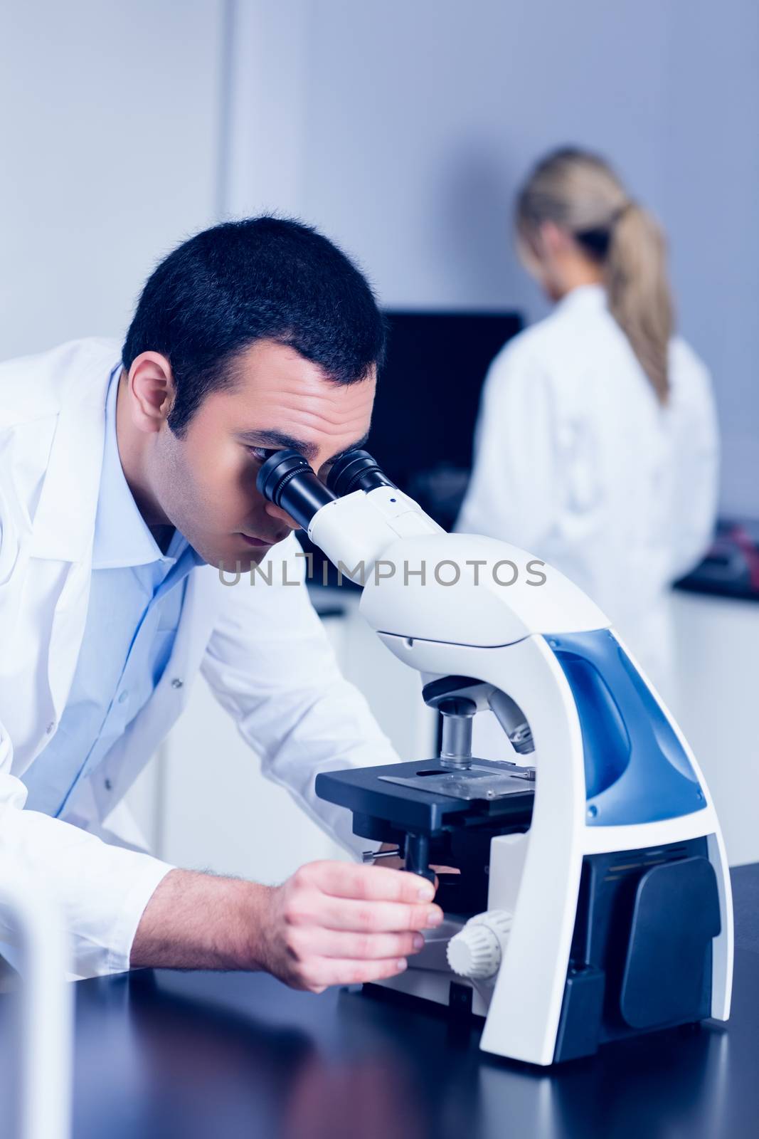 Science student looking through microscope in the lab by Wavebreakmedia