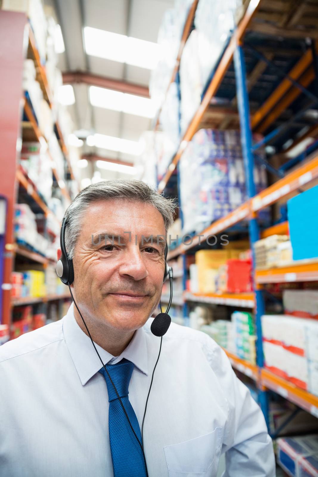 Warehouse manager giving orders on headset in a large warehouse