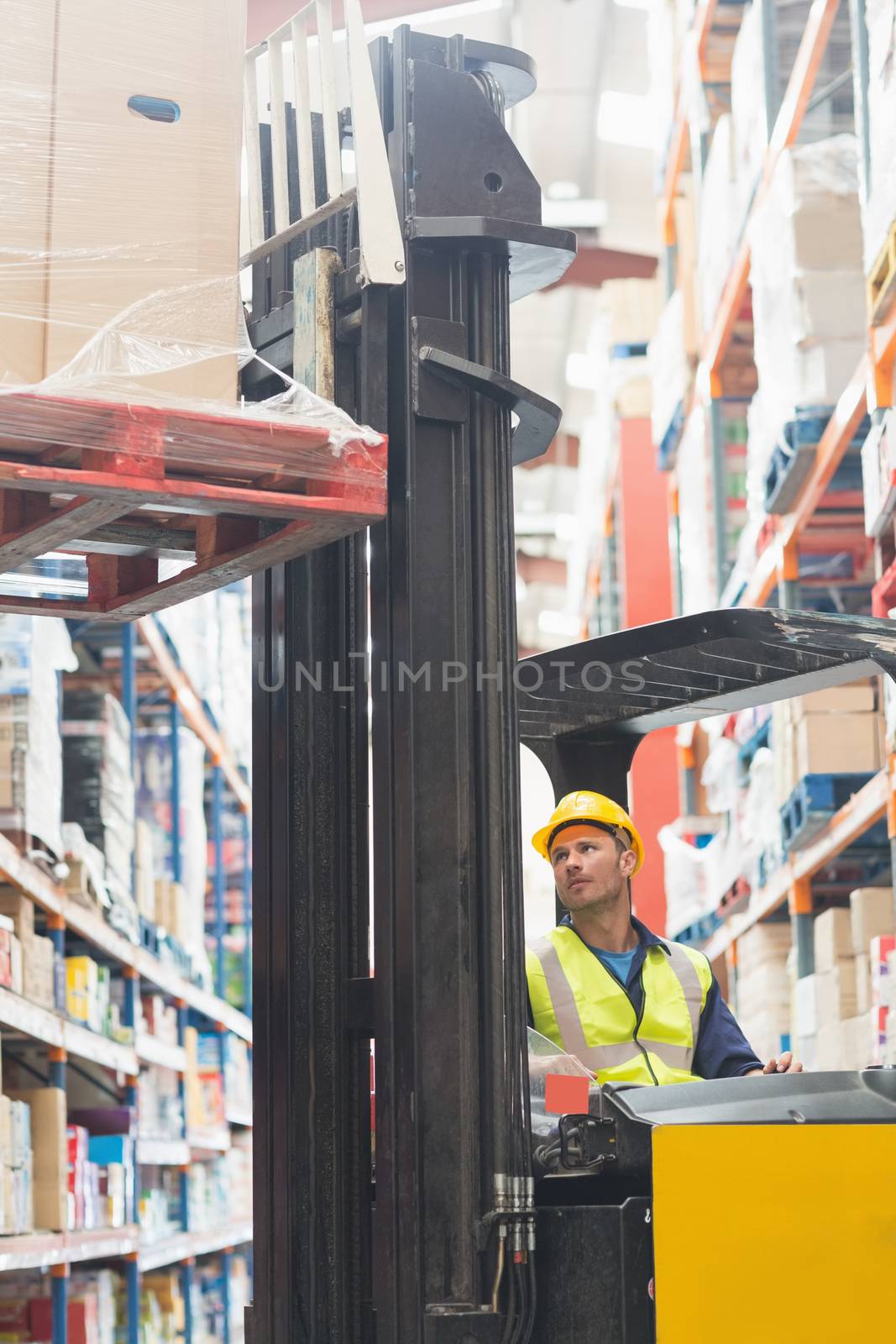 Focused driver operating forklift machine in warehouse