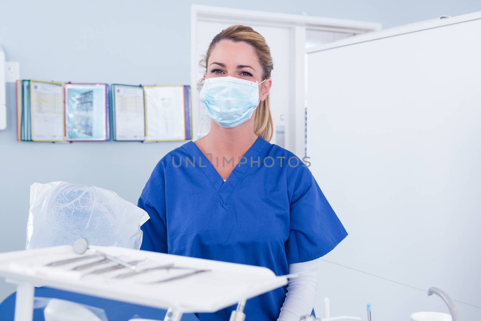 Dentist in mask behind tray of tools at the dental clinic