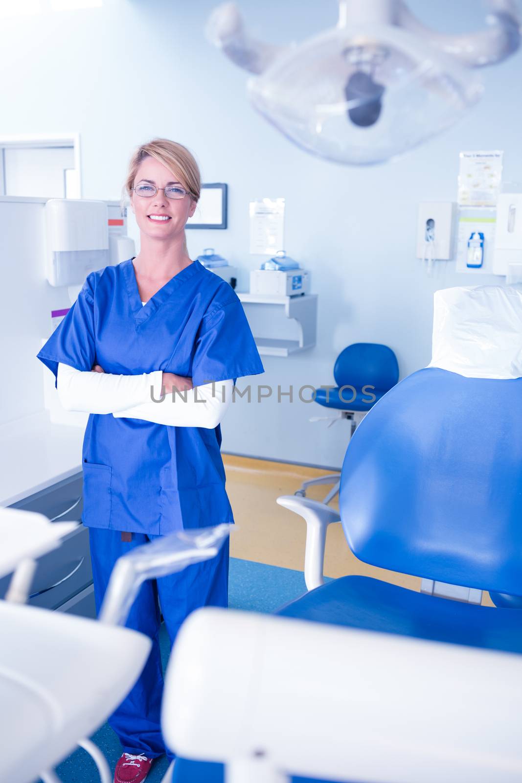 Smiling dentist standing with arms crossed at the dental clinic