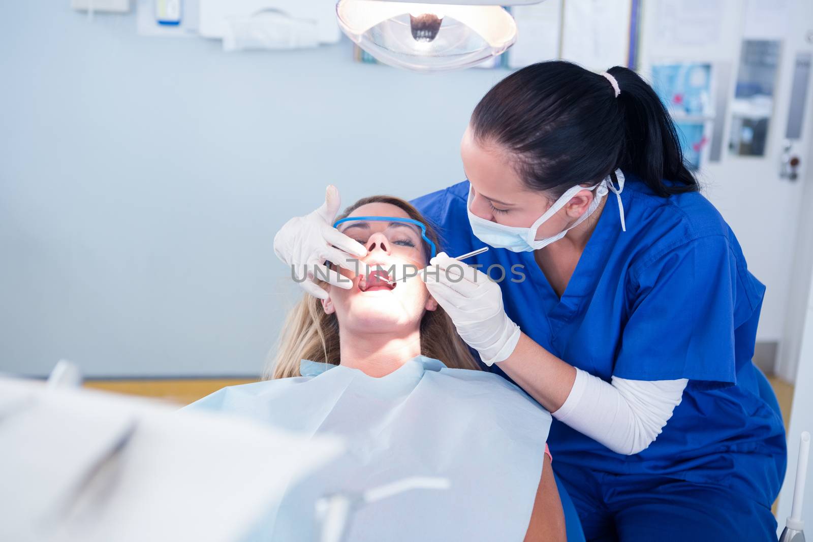 Dentist examining a patients teeth under bright light at the dental clinic