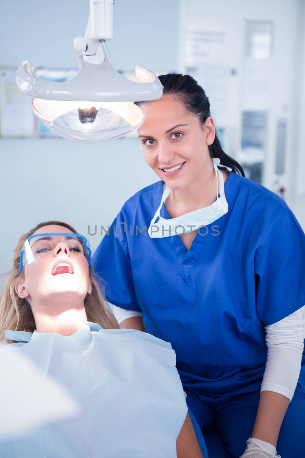 Dentist smiling at camera with patient in the chair by Wavebreakmedia