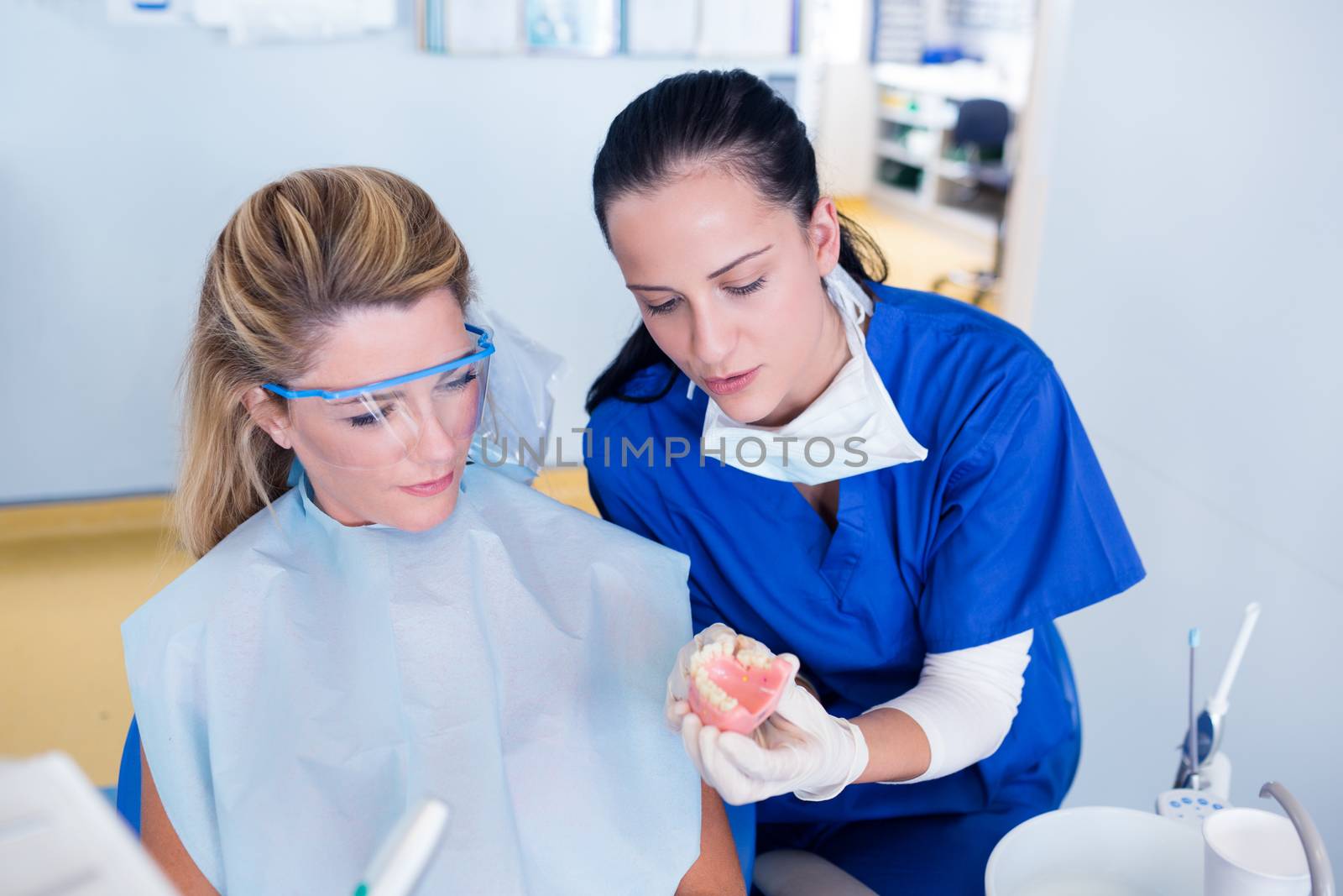 Dentist showing patient model of teeth at the dental clinic