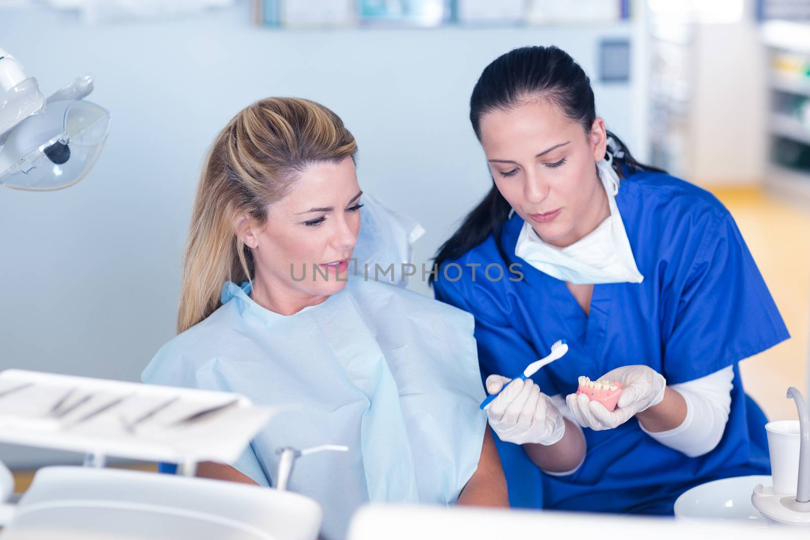 Dentist showing patient model of teeth by Wavebreakmedia