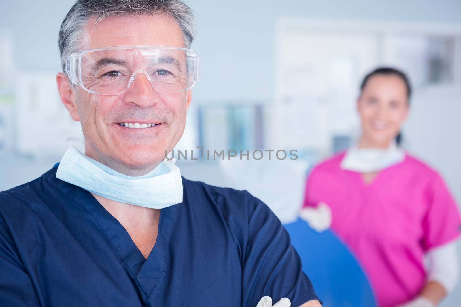 Smiling dentist with protective glasses at the dental clinic