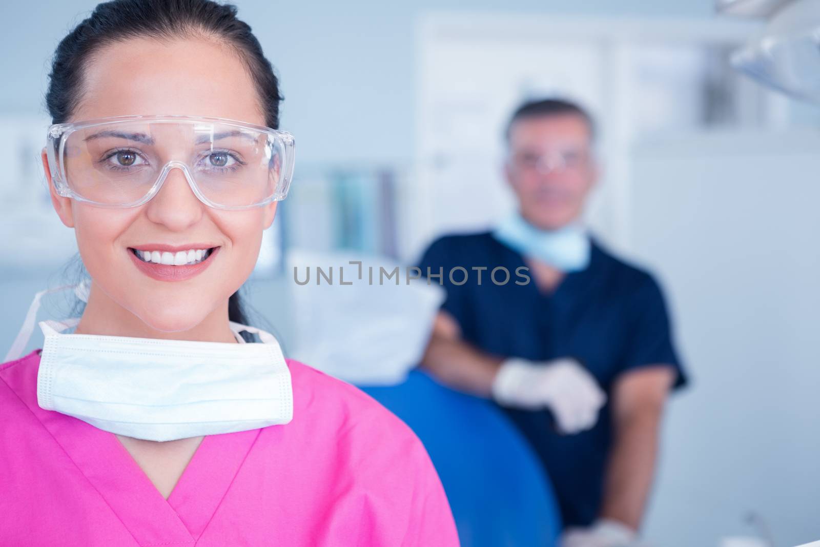 Smiling assistant with protective glasses at the dental clinic