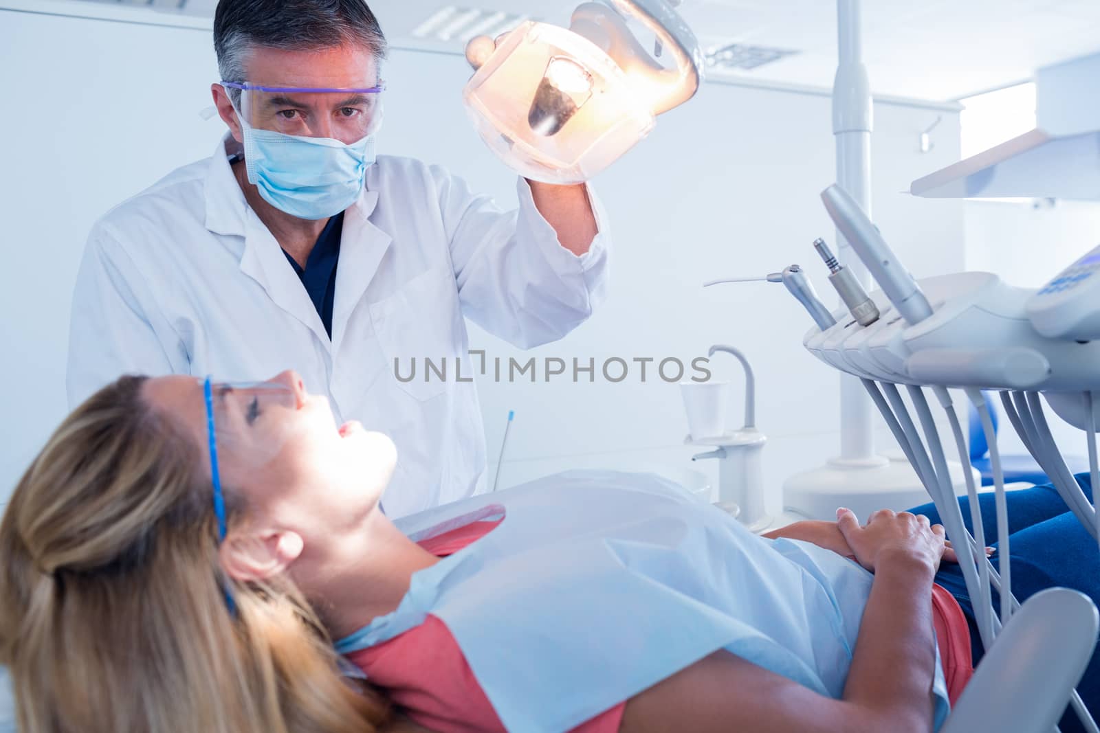 Dentist examining a patients teeth in chair under bright light by Wavebreakmedia