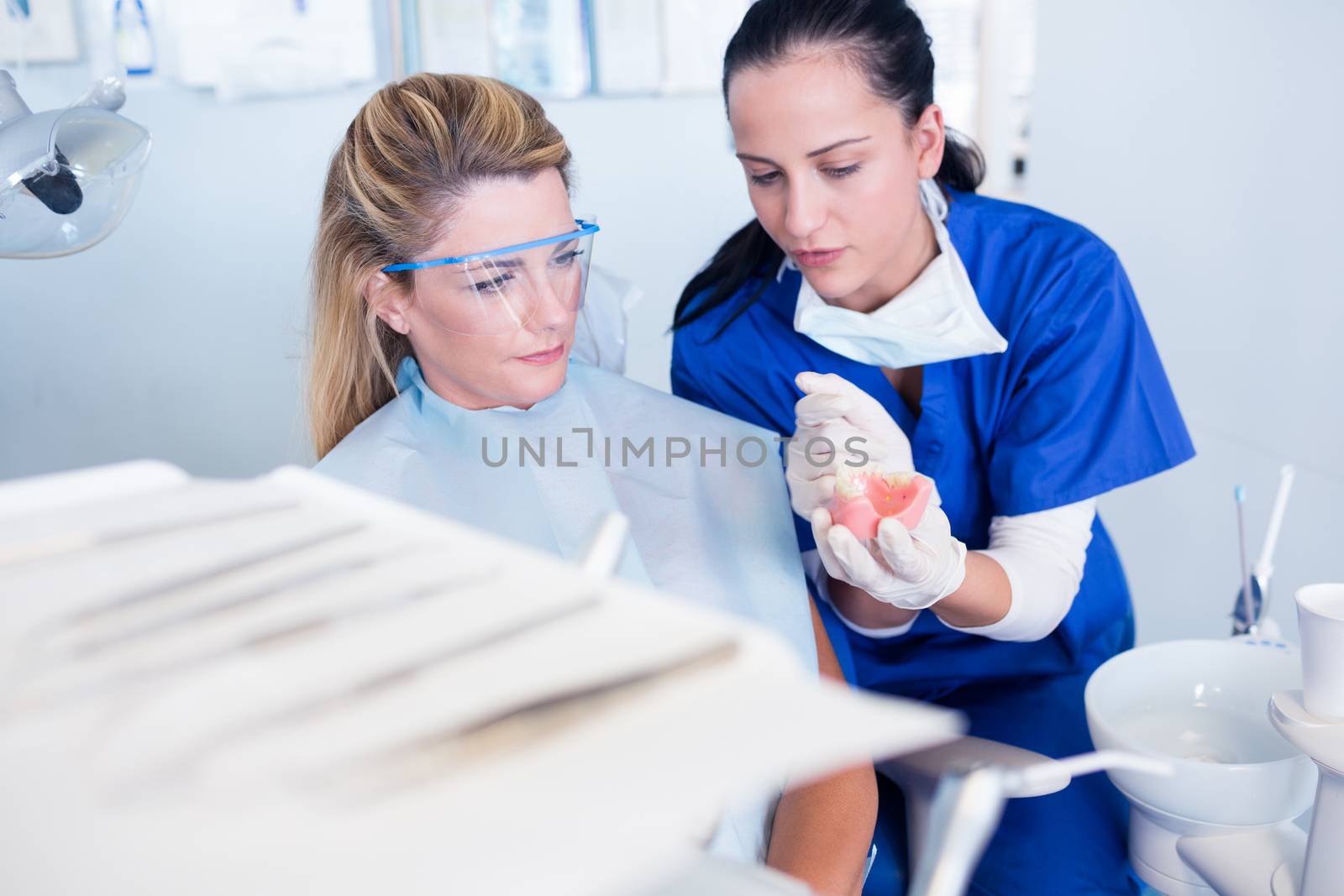 Dentist showing patient model of teeth at the dental clinic