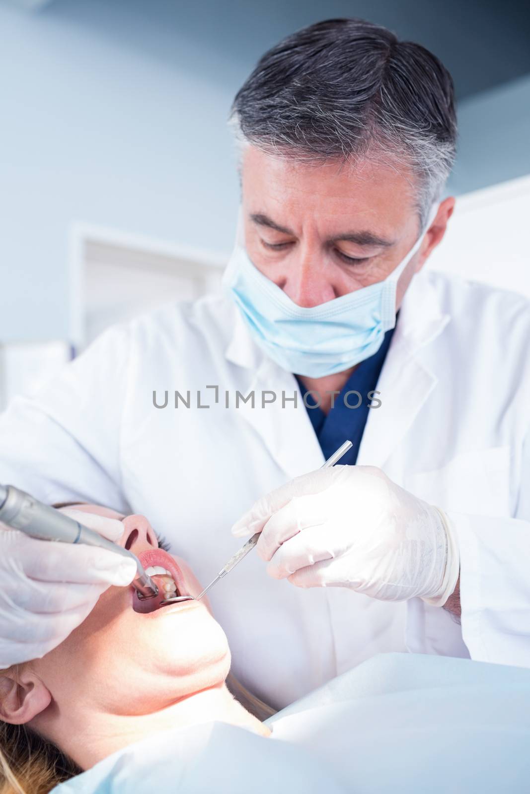 Dentist examining a patients with angled mirror at the dental clinic