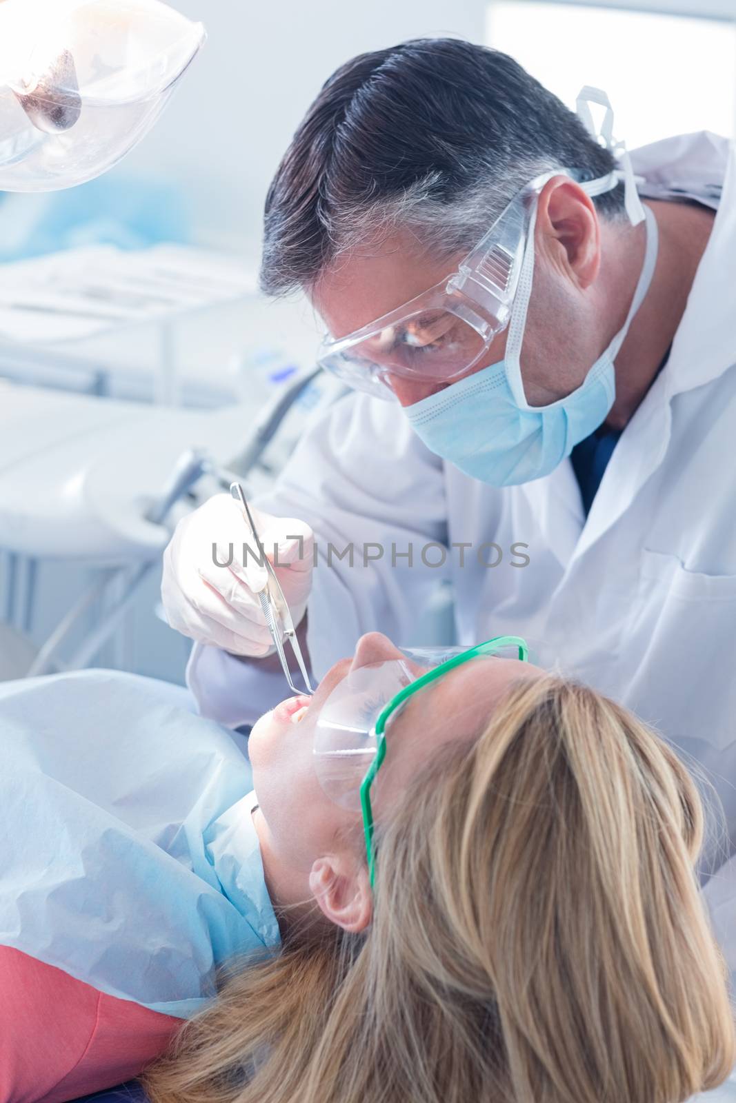 Dentist in surgical mask and gloves holding tool at the dental clinic