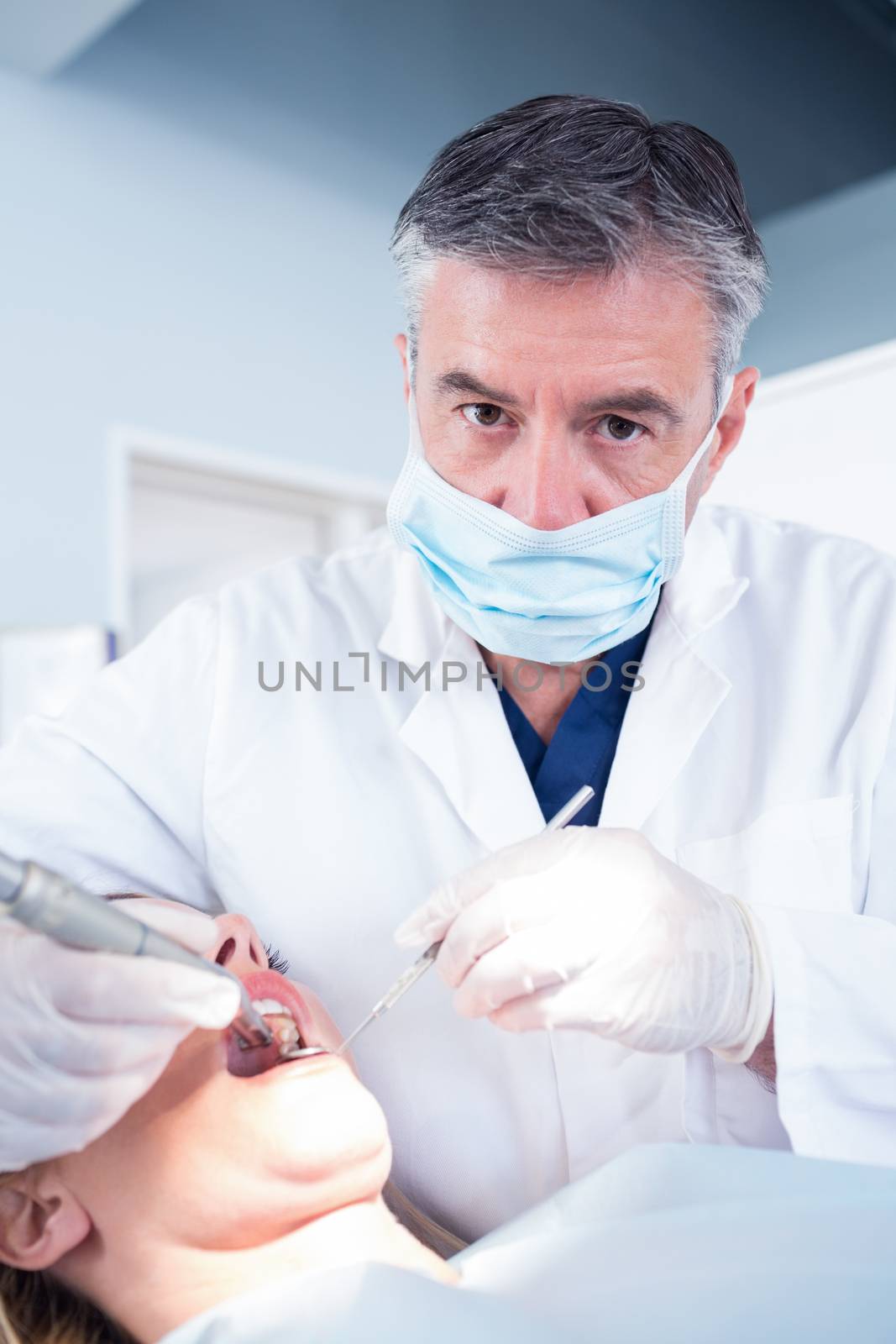 Dentist examining a patients looking at camera at the dental clinic