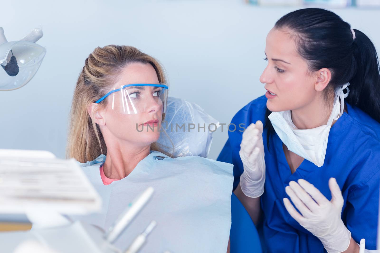 Dentist talking with patient in chair by Wavebreakmedia