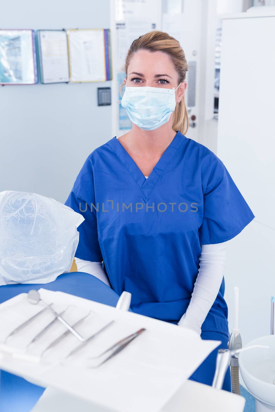Dentist in mask behind tray of tools by Wavebreakmedia