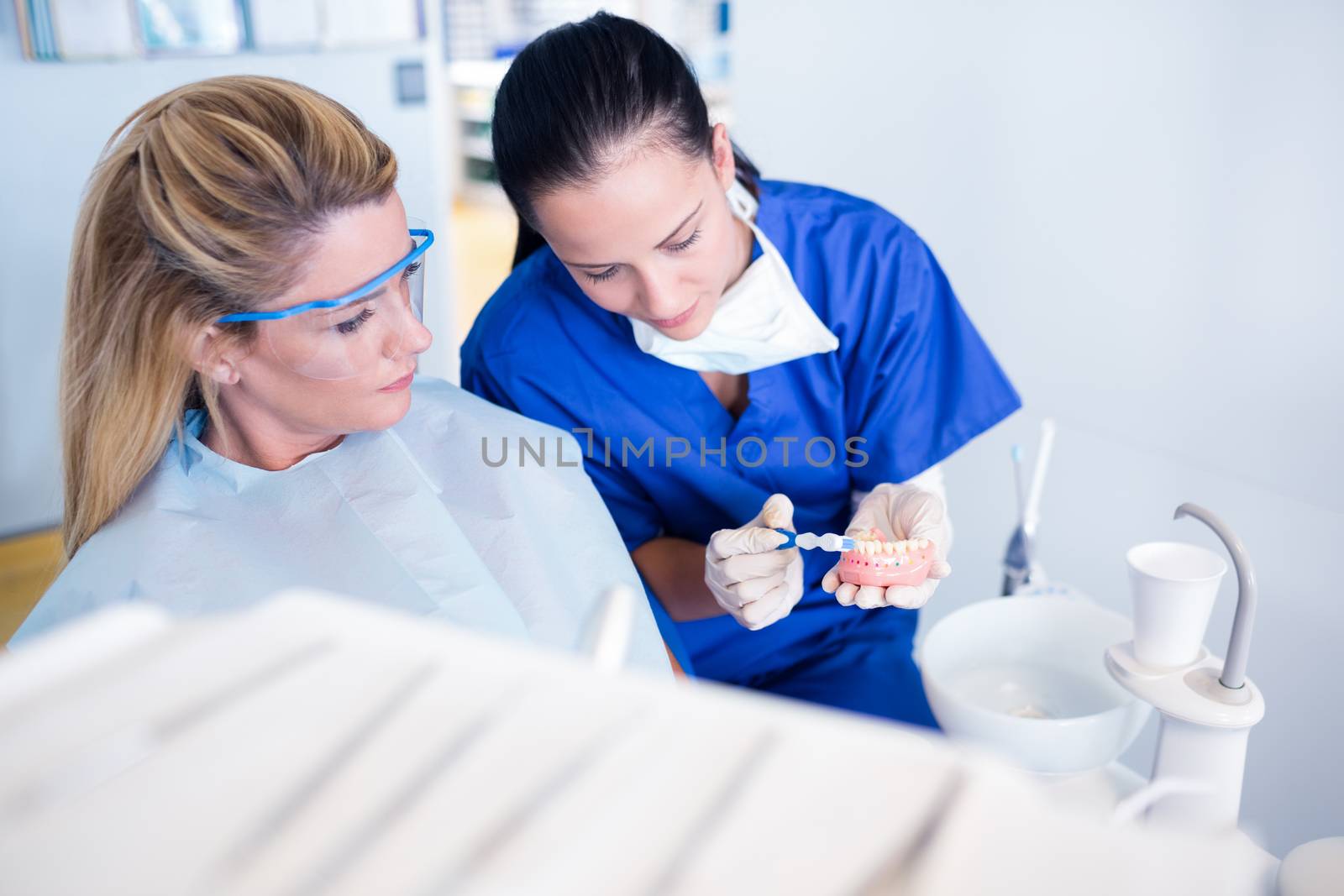 Dentist showing patient model of teeth at the dental clinic