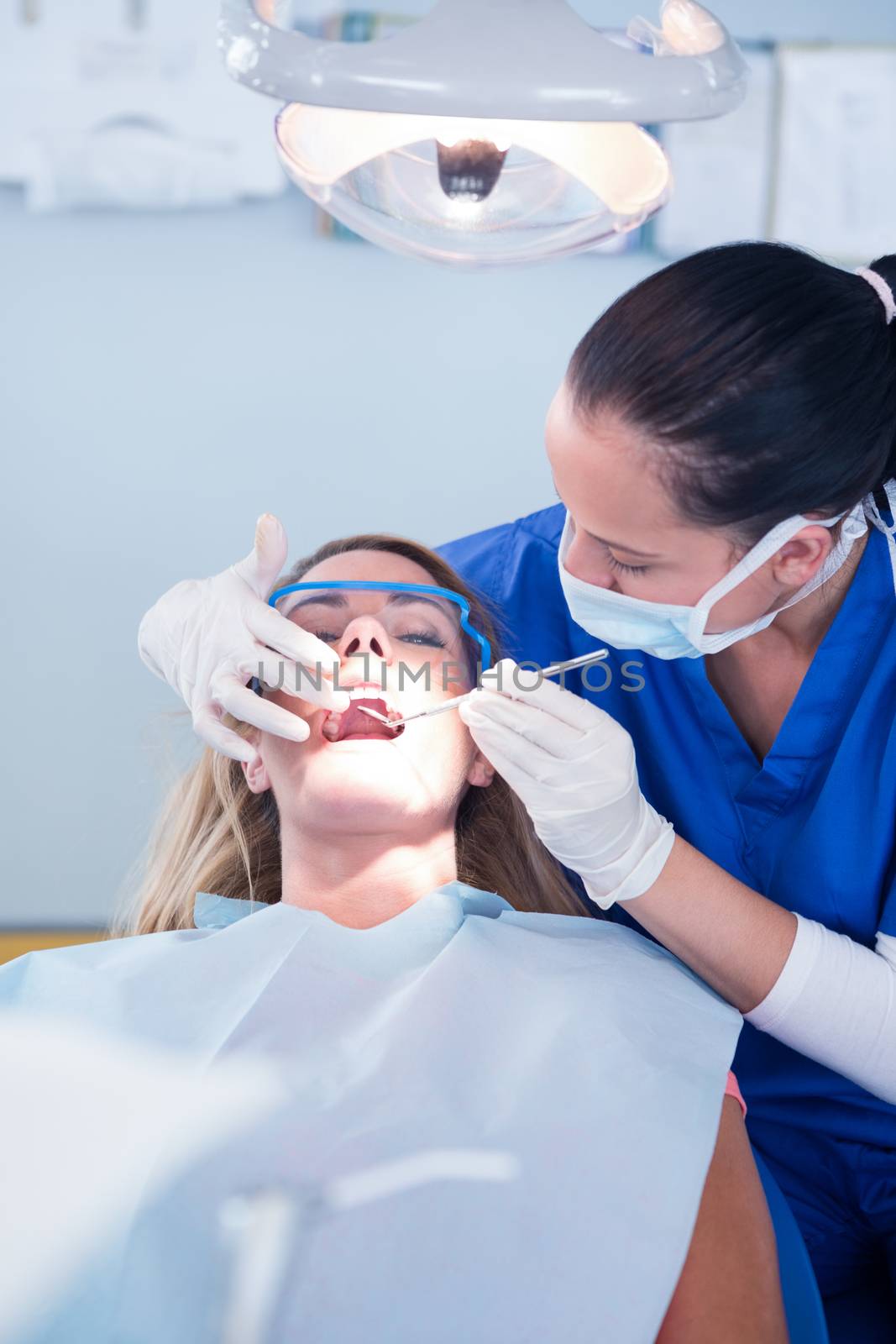 Dentist examining a patients teeth under bright light at the dental clinic