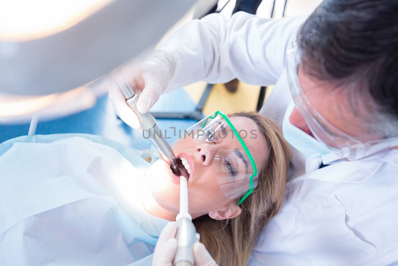 Dentist examining his patient with a suction hose by Wavebreakmedia